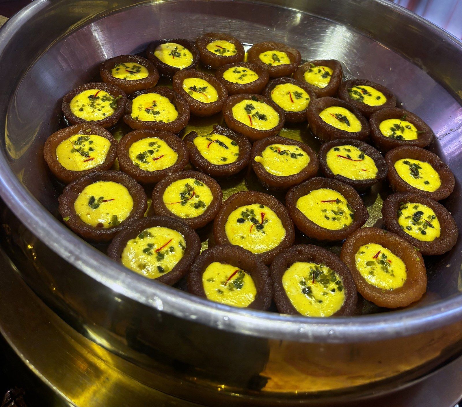 Malpua baskets filled with saffron rabdi in a steel handi