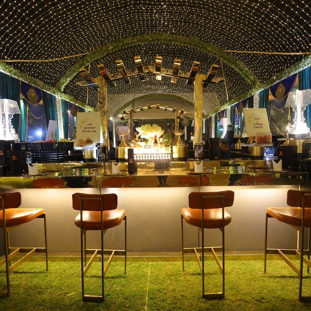 A bar counter with leather stools under a canopy of lights, menu cards on the counter