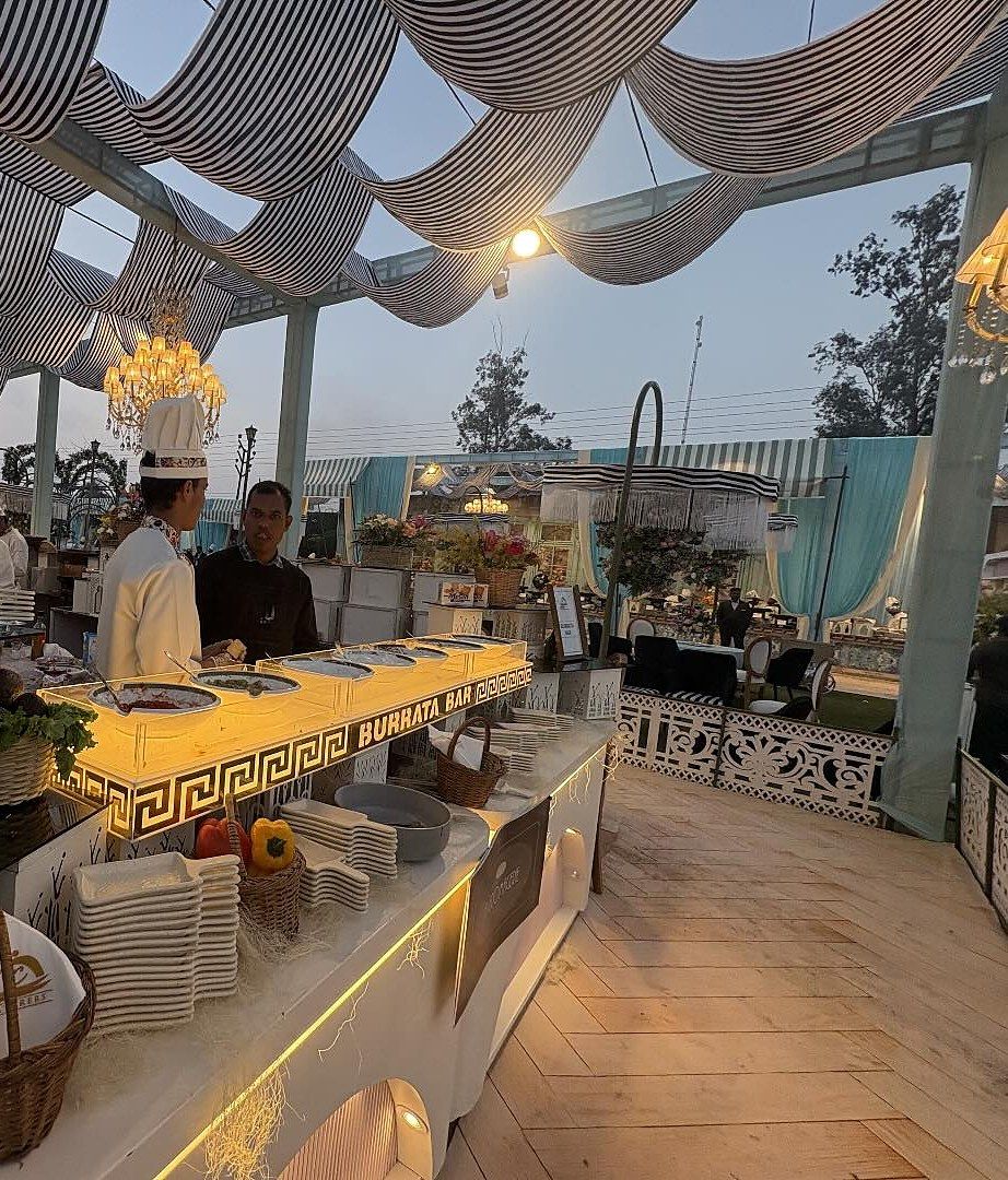 The Burrata Bar counter with a gold key-pattern front and chandeliers under striped drapes