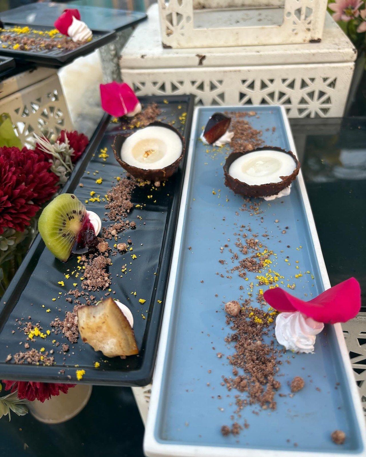 Coconut-shell desserts and meringue on slate plates, petals scattered around