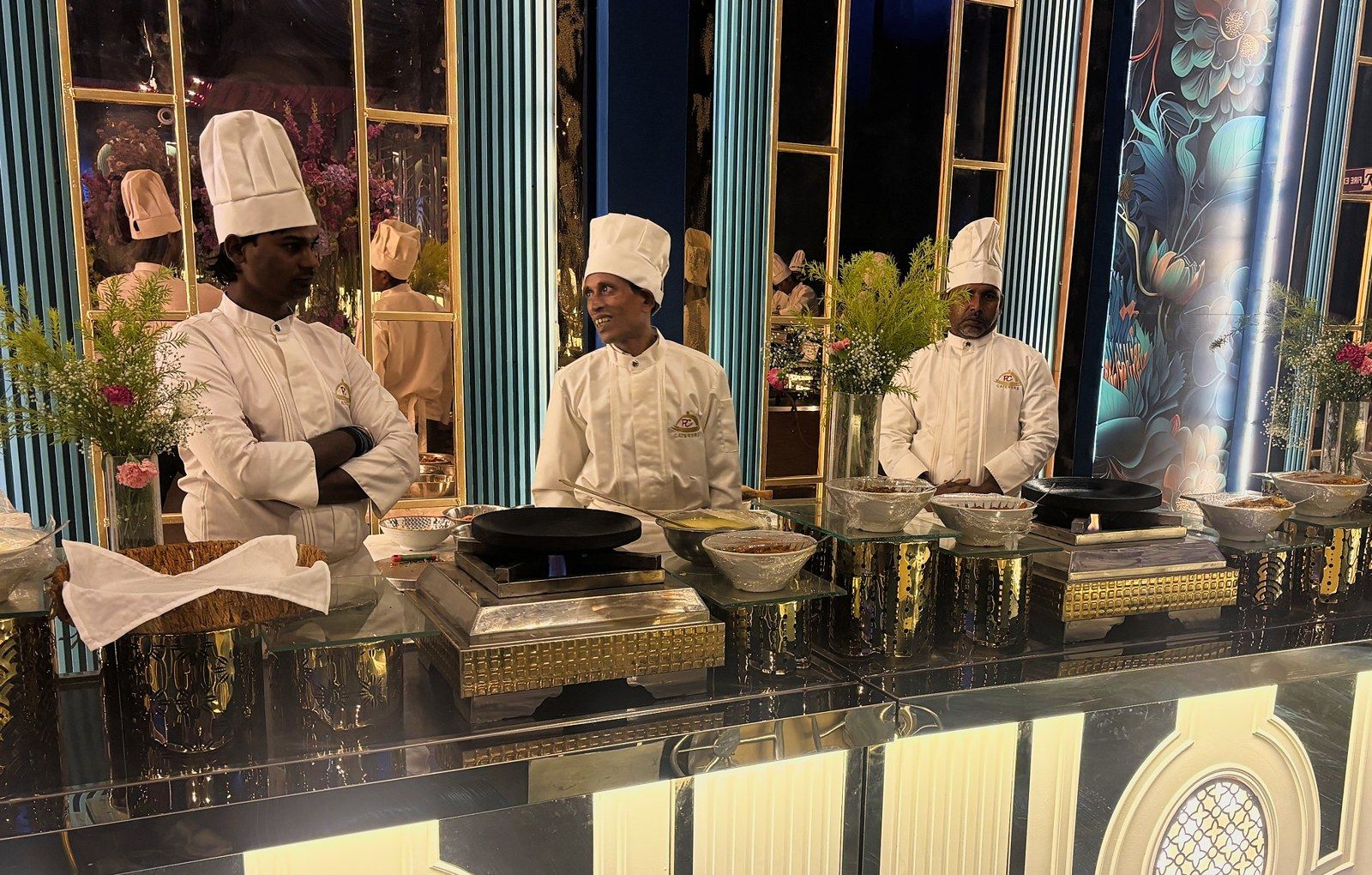 Three chefs at a lit jali counter